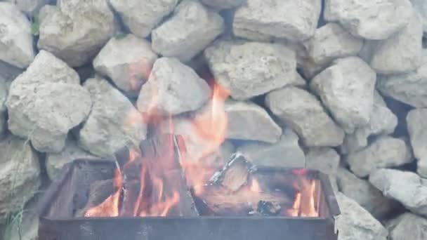 Cocina, cocina oriental, incendios forestales, concepto de incendio provocado - encender fuego y carbones en la parrilla metálica negro para fumar y freír carne y alimentos vegetales en calor de fondo al aire libre de piedras blancas — Vídeos de Stock