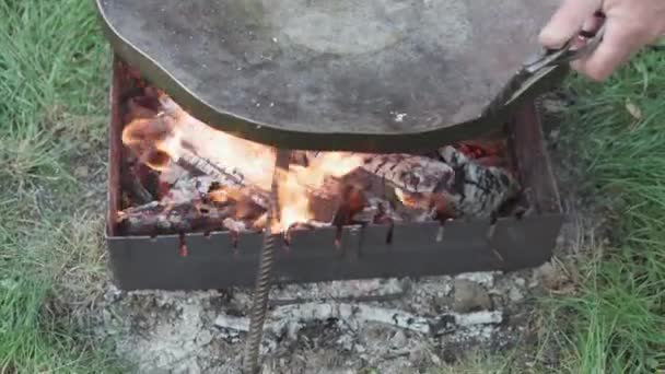 카페와 레스토랑, 요리, 피크닉, 동양 요리 컨셉트 - 야외 모닥불 위에서 요리를 위한 거대 한 프라이팬을 클로즈업으로 준비하는 모습: 고기, 야채, 생선및기 타요리. — 비디오