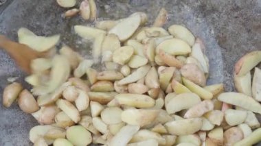 Kafeler ve restoranlar, yemek pişirme, piknik, doğu mutfağı konsepti - patatesleri, kamp ateşi üzerinde pişirmek için büyük bir tavada ahşap spatulayla karıştırmak: et, sebze diğer yemekler.