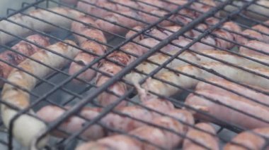 Kafeler ve restoranlar, yemek pişirme, piknik, doğu mutfağı konsepti - yakın plan sosisler ızgarada ızgarada kızartılmış ve ızgara kömürde kızartılmış. Dışarıdaki erkeklerin elleri yemeğe hazırlanıyor..