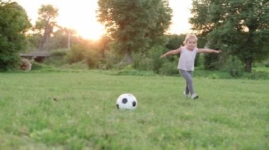 Çocukluk, oyunlar ve eğlence, spor, fiziksel kültür, açık hava konsepti - küçük çocuklar el ele tutuşup uçağın gün batımında parktaki açık yeşil çimlerde koşup düşüşünü tasvir ediyorlar.