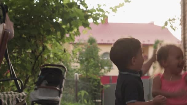 Infanzia, infanzia, sviluppo, vacanza estiva, concetto-Tre bambini di tre anni si divertono e amichevole cattura bolle di sapone nel cortile del giardino presso il cottage. I bambini giocano insieme fuori — Video Stock