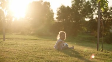 Çocukluk, oyunlar ve eğlence, spor, fiziksel kültür, açık hava konsepti - küçük sarışın kız güneş batarken açık yeşil çimlerde siyah beyaz topla futbol oynuyor..