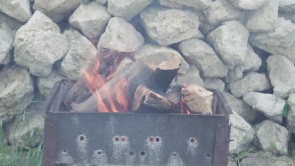 Vaření, orientální kuchyně, lesní požáry, žhářský koncept - zapalování ohně a uhlí v černém kovovém grilu pro uzení a smažení masa a zeleniny v teple venkovního prostředí z bílých kamenů — Stock video