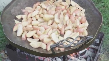 Kafeler ve restoranlar, yemek pişirme, piknik, doğu mutfağı konsepti - patatesleri, kamp ateşi üzerinde pişirmek için büyük bir tavada ahşap spatulayla karıştırmak: et, sebze diğer yemekler.