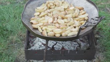 Kafeler ve restoranlar, yemek pişirme, piknik, doğu mutfağı konsepti - kamp ateşi üzerinde yemek pişirmek için büyük kızartma tavasında yakın plan patates kızartma.