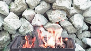 Yemek pişirme, doğu mutfağı, orman yangınları, kundakçılık kavramı - beyaz taşların arka planında sigara içmek ve et ve sebze kızartmak için siyah metalik ızgarada ateş ve kömür yakmak