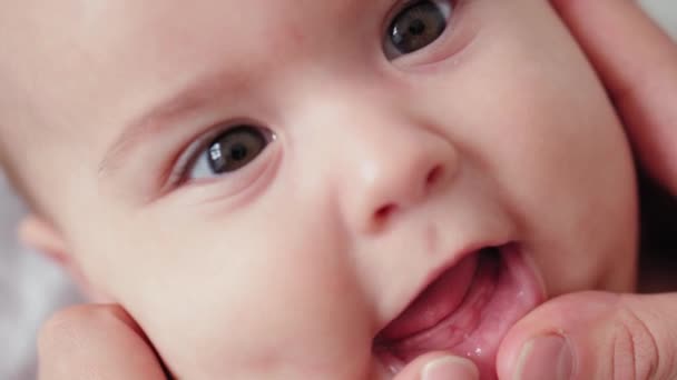 Medicine, pediatrics, dentistry, newborns concept - mom open baby mouth showing first milk baby tooth erupted from swollen gums. super close-up portrait of baby smiling with his mouth open with joying — Stock Video