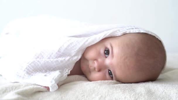 Barndom, daglig rutin, hygien spädbarnskoncept - Närbild Happy kid handduk på vit bakgrund efter att ha badat. nyfödd efter dusch på magen på sängen. Väckningstid före sänggåendet — Stockvideo
