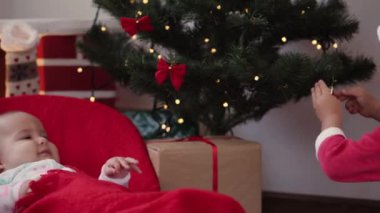 Xmas, kış, yeni yıl, kutlama, aile konsepti - iki kardeş yumuşak battaniyeye sarılmış bebek ve Noel kıyafetleri giymiş erkek kardeş ve şömine süslenmiş Noel ağacı başında şapka oyunu