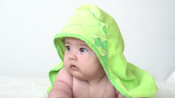 Дитинство, повсякденна рутина, концепції гігієни немовлят - крупним планом Щасливий дитячий рушник зеленої жаби на білому тлі після прийняття ванни. новонароджений після душу на шлунку на ліжку. час пробудження дитини — стокове відео