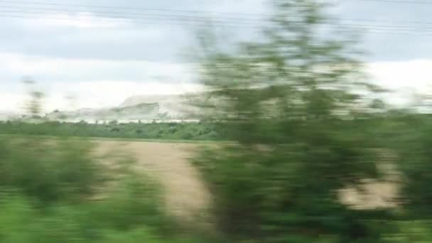 Transporte, viajes, carretera, ferrocarril, paisaje, concepto de comunicación - vista desde la ventana del tren de velocidad en el paisaje de la hermosa carretera de campo de la naturaleza con cantera de piedra en el tiempo nublado opaco noche de verano — Vídeo de stock