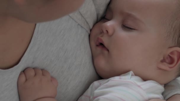 Medicina, salud, familia, inocencia, pediatría, felicidad, conceptos infantiles - Primer plano Joven madre feliz dormir 7 meses hija roca bebé en brazos y cantar canción de cuna sentado en la guardería en — Vídeo de stock