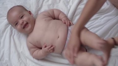 Tıp, sağlık, aile, masumiyet, pediatri, mutluluk, bebek konseptleri - anne bebeklere sırt çevirmeyi, masaj ve egzersiz yapmayı, evde beyaz yatakta cilt veya göğüs masajı yapmayı öğretiyor.