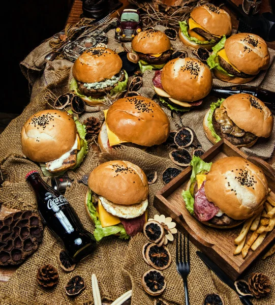 restoranda ahşap tahta üzerinde birçok hamburger, abur cubur ve karanlık beton üzerinde fast food kavramı üst görünümü - stok görüntü arka plan