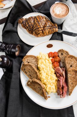 İngiliz kahvaltısı yumurta, domates, mantar, pastırma, fasulye, kruvasan ve cofe