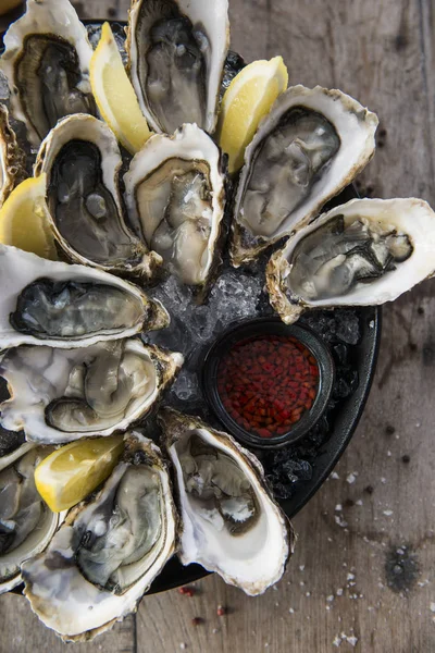 plate of oysters on wooden table with red sous