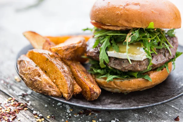 Beef burger with cheese and fries on wood table