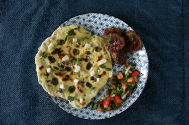 Bitmiş tabağın fotoğrafı. Tabağın üzerinde taze sebzelerle kaplı taze pişmiş bir ekmek var, köftenin yanında. Fotoğraf gün ışığında oturma odasında, mutfakta çekilmişti..