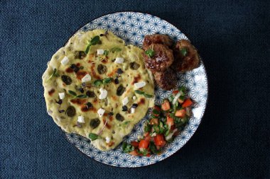 Bitmiş tabağın fotoğrafı. Tabağın üzerinde taze sebzelerle kaplı taze pişmiş bir ekmek var, köftenin yanında. Fotoğraf gün ışığında oturma odasında, mutfakta çekilmişti..