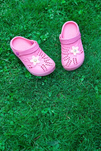 Roze kid's slippers op groen gazon. Kopieer ruimte. Bovenaanzicht, gelegen op de top van het frame. Verticaal. Begrip van eenheid met de natuur. Mock up for children's winkel product, Moederdag blog, ouderschap magazine. — Stockfoto