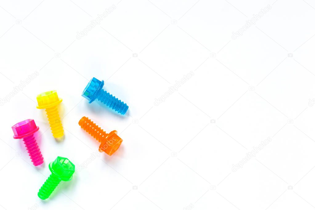 Colored translucent toy bolts on white background. Flat lay. Concept World Dad's Day, unisex toys for early development, role-playing games. Layout for social media, toy stores. Copy space