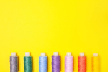 El sanatları arka planı. Kopya alanı ile sarı arka planda çok renkli iplik makaraları ayarlayın. Iğne, nakış, dikiş için aksesuarlar. Düz yatıyordu. Üst görünüm. Öğeler alt ucunda sıralanır