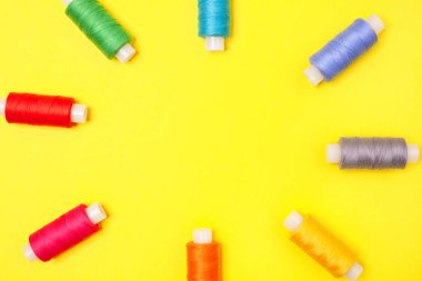 El sanatları arka planı. Kopya alanı ile sarı arka planda iplik form çerçevesi çok renkli makaralar ayarlayın. Iğne, nakış, dikiş için aksesuarlar. Düz yatıyordu. Üst görünüm.