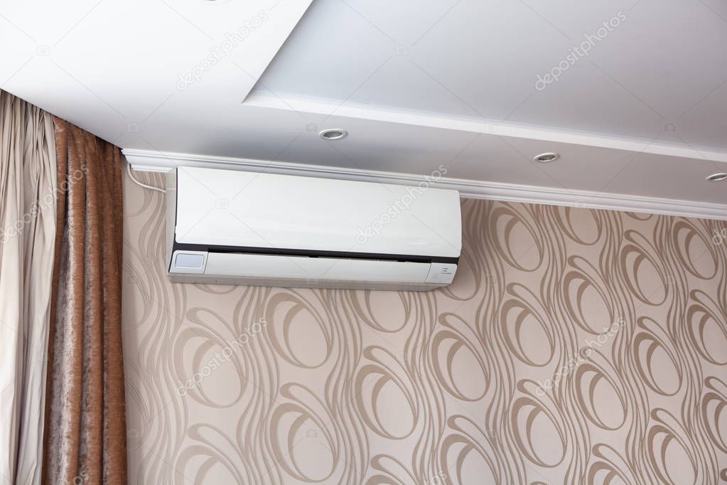 Air conditioning on the wall inside the room in apartment, switched off. Interior in calm beige tones.