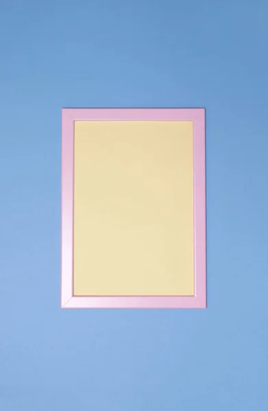 Leeg roze PhotoFrame met geel papier binnenin op blauwe achtergrond. Kopieerruimte. Bovenaanzicht. Verticale. — Stockfoto