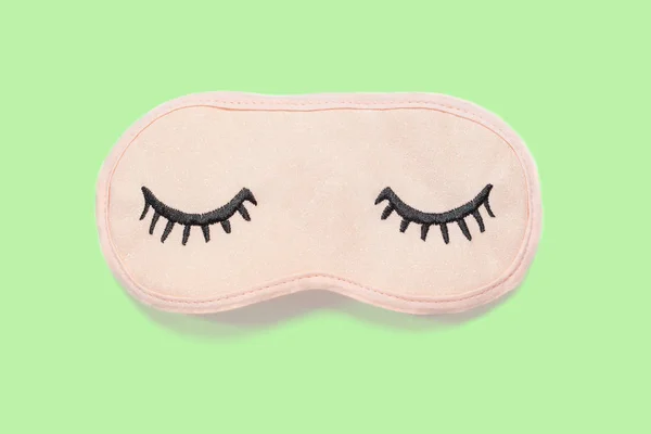 Pastel roze slaap masker met gesloten ogen geborduurd op het met wimpers op pastel groene achtergrond. Top uitzicht, vlakke lag. Concept van levendige dromen. Accessoires voor meisjes en jonge vrouwen. Minimalistische stijl — Stockfoto