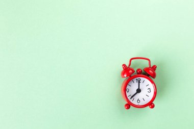 Kopya alanı ile ışık pastel yeşil arka plan kırmızı küçük çalar saat, düz yatıyordu. Minimal tarzı. Blog için şablon. Yaşam tarzı. Zaman yönetimi kavramı, önemli şeyler için serbest zaman