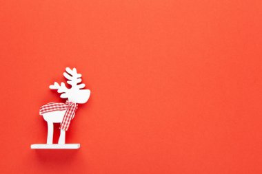 Noel süsü, kırmızı arka planda kareli eşarplı oyuncak beyaz geyik ve fotokopi alanı. Şenlikli, yeni yıl konsepti. Yatay, düz yatay. Asgari düzeyde. Üst görünüm