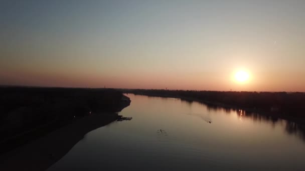 Rückwärts im Sonnenuntergang über dem See, ruhiges Wasser und eine Spiegelung der Sonne, Flug über dem Ruderteam beim Üben