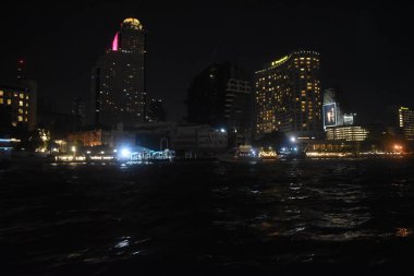 Teknede yolculuk yapmak, gece vakti nehir yansıması, şehrin gece ışığını izlemek.