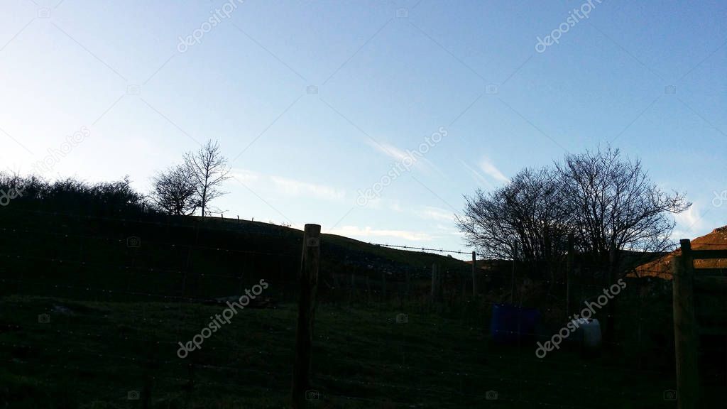 silhouette shap of trees on the hill with blue sky background 