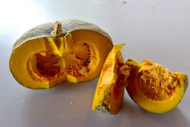 Dilimler ve tohumlu yarım balkabağı, beyaz arka planda izole edilmiş, organik sebze.