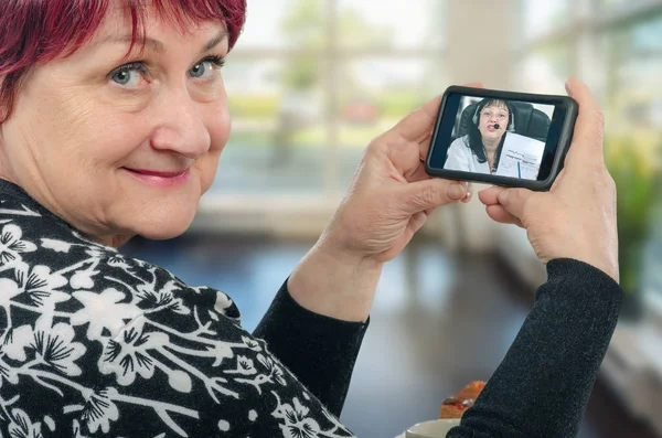 Mature woman of over 60 listens to the advice of  virtual doctor which explains her latest analysis. The virtual patient smiles and happy to listens that everything is alright. Her face says thank you virtual doc
