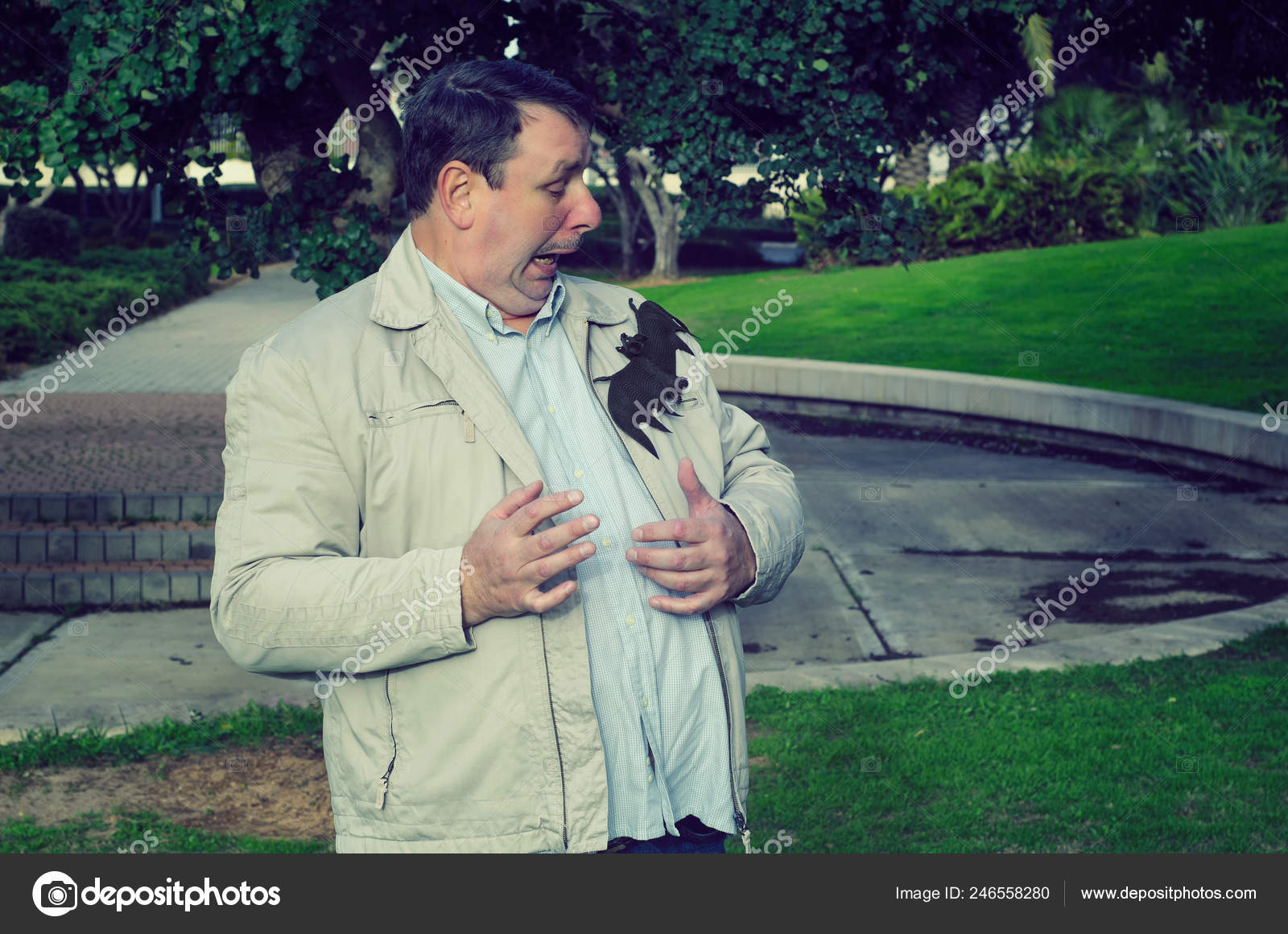 Mature man is very scared because big bat has landed on his jacket