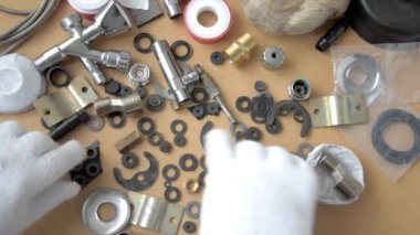 Yedek parça ile masaüstünde doğru cıvata ve somun arayan bir tesisatçı. Üst görünüm.