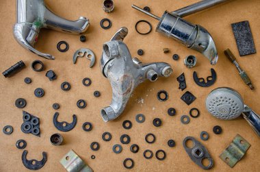 Ağır kalcified musluk tesisatçı masasında çeşitli sıhhi tesisat öğeleri arasında görünür. Birçok farklı kauçuk contalar vardır. Üst görünüm.