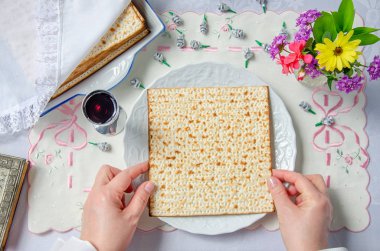 Pastanesi üzerinde tablonun üst görünümü. Bir kadın matzah 'u beyaz bir plakaya koyar..
