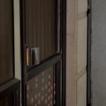 Woman in black clothes with obsessive-compulsive disorder (OCD). She is assured there are a lot of germs on the door handle, therefore, she applies a hygiene napkin on it. Then she opens the entrance door.