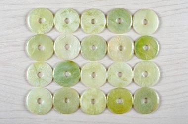 Twenty butter jade round donut-shaped stones are stowed four rows. Five pieces in each one. Top view. clipart