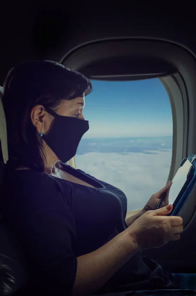 Starší Žena Ochranné Masce Letí Letadlem Během Pandemie Pečlivě Něco — Stock fotografie