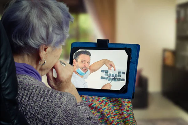 The caring dental surgeon shows his remote elderly patient x-rays image. The senior adult woman listens to the telemedicine dentist very carefully.