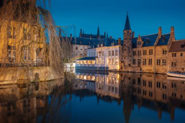 Akşam yağmurdan sonra Bruges sokaklarında. Onze Lieve 'in gece manzarası. Brugge, mavi gökyüzünün arka planına karşı. Belçika.