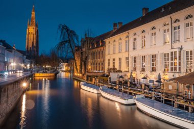 Akşam yağmurdan sonra Bruges sokaklarında. Onze Lieve 'in gece manzarası. Brugge, mavi gökyüzünün arka planına karşı. Belçika.