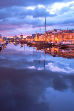 Gün batımında su hortumları, değirmenleri, gemiler ve teknelerle Leiden şehrinin kanallarını izleyin. Hollanda 'nın Leiden şehrinde, gemileriyle şehir kanalının görüntüsü.