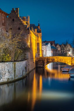 Akşam yağmurdan sonra Bruges sokaklarında. Onze Lieve 'in gece manzarası. Brugge, mavi gökyüzünün arka planına karşı. Belçika.